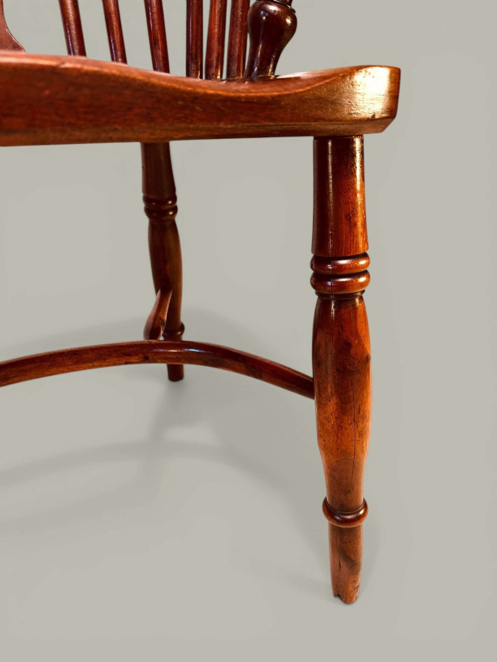 A mid-19th-century Windsor armchair crafted from polished yew and elm wood, featuring a hoop back, a pierced central splat, swept arms, and turned legs. View VI