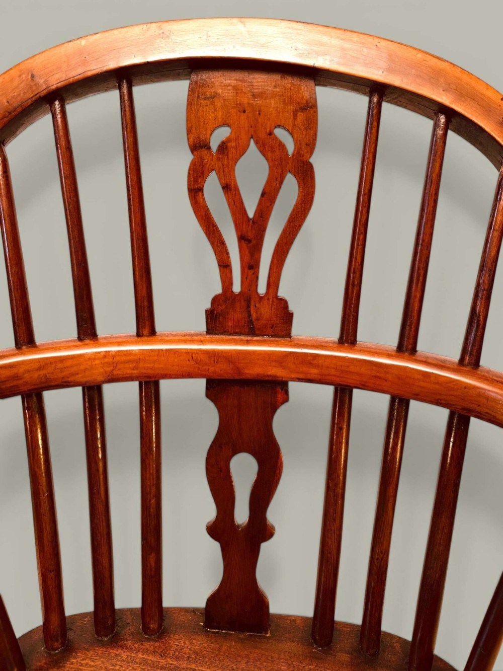 A mid-19th-century Windsor armchair crafted from polished yew and elm wood, featuring a hoop back, a pierced central splat, swept arms, and turned legs. View VII