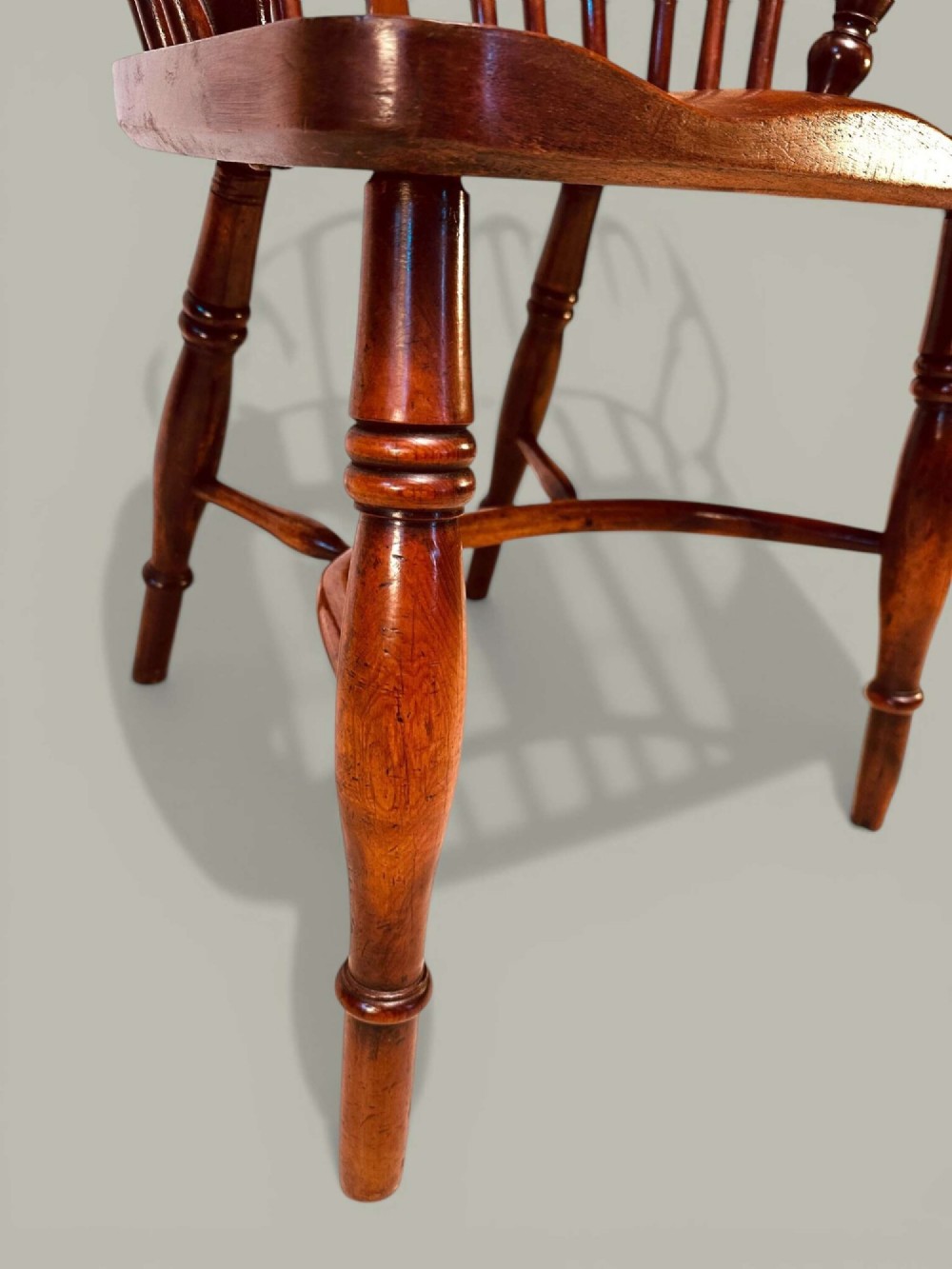 A mid-19th-century Windsor armchair crafted from polished yew and elm wood, featuring a hoop back, a pierced central splat, swept arms, and turned legs. View IX