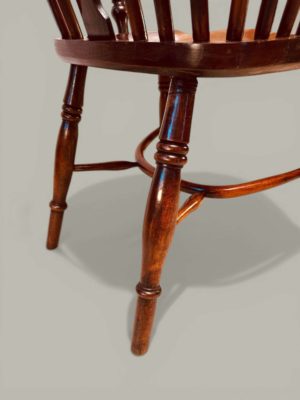 A mid-19th-century Windsor armchair crafted from polished yew and elm wood, featuring a hoop back, a pierced central splat, swept arms, and turned legs. View X