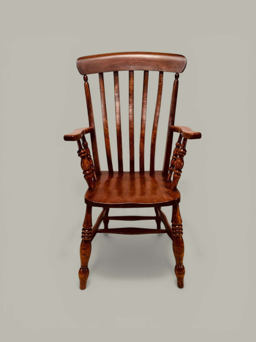 A late nineteenth-century wooden Windsor armchair featuring a curved slat back rest, turned legs, an H-stretcher, and shaped armrests finished in warm brown timber tones. View III