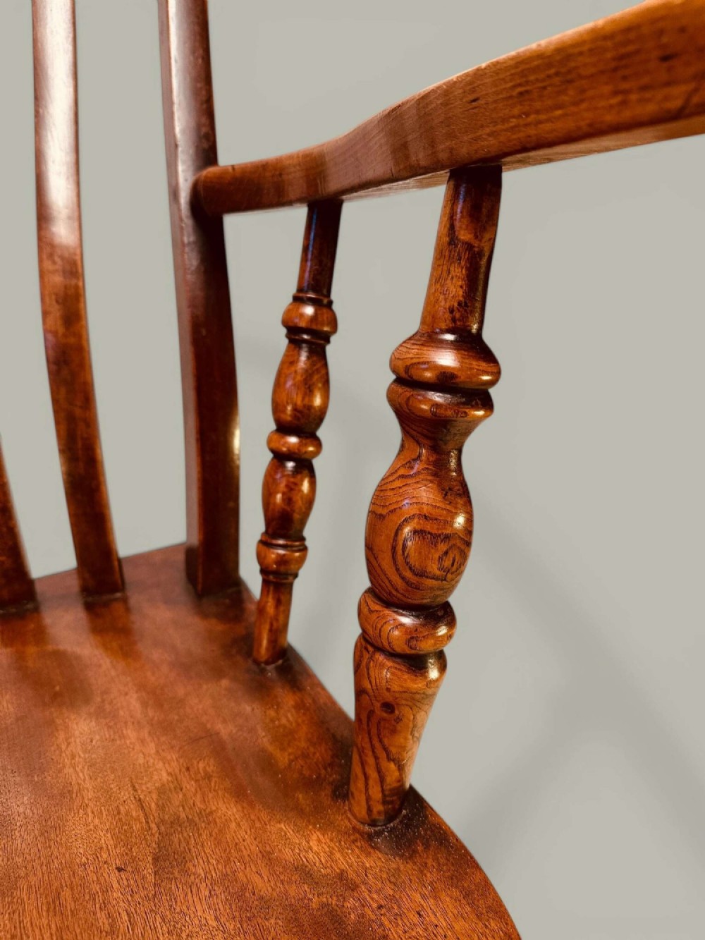A late nineteenth-century wooden Windsor armchair featuring a curved slat back rest, turned legs, an H-stretcher, and shaped armrests finished in warm brown timber tones. View VII