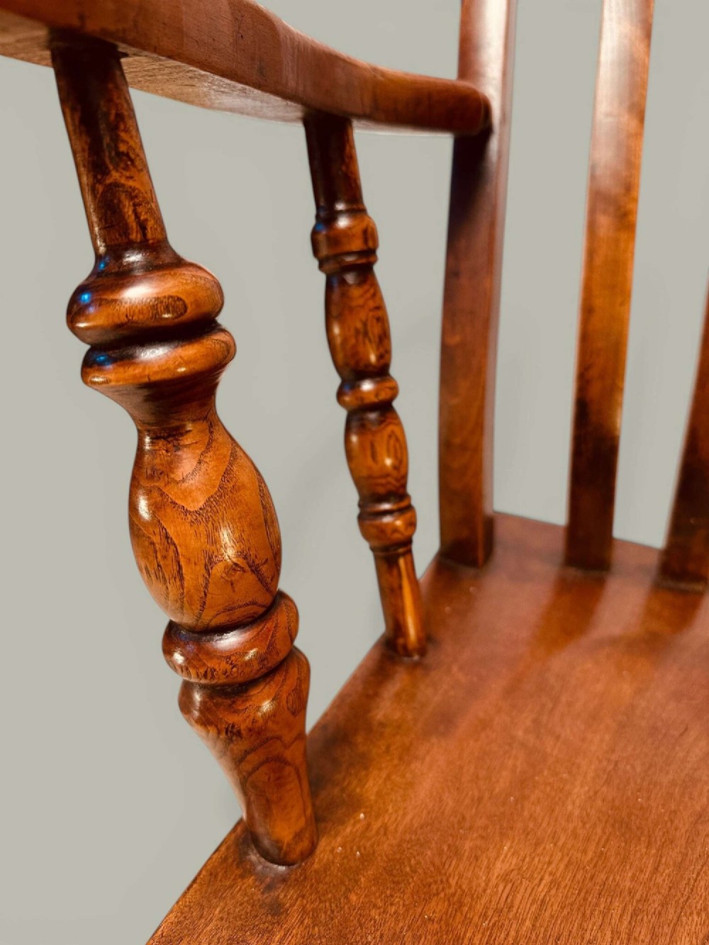 A late nineteenth-century wooden Windsor armchair featuring a curved slat back rest, turned legs, an H-stretcher, and shaped armrests finished in warm brown timber tones. View VIII