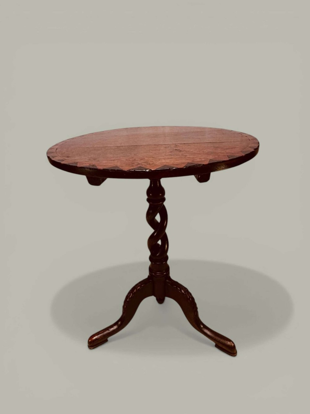 An antique dark oak circular tilt-top pedestal table featuring a geometric inlaid border, a spiral turned column, and carved tripod legs. View II