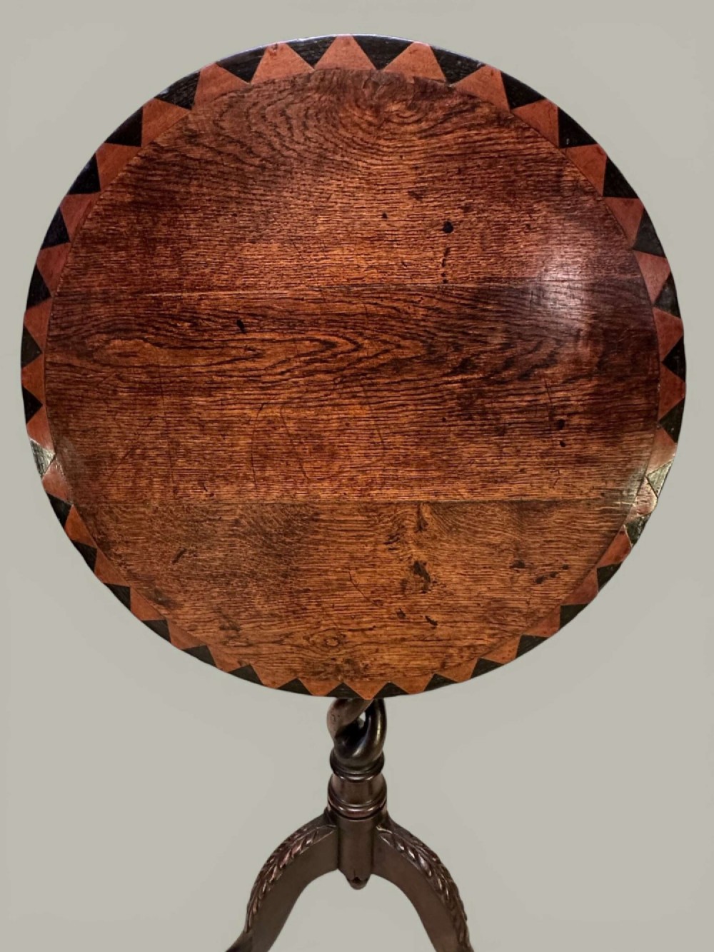 An antique dark oak circular tilt-top pedestal table featuring a geometric inlaid border, a spiral turned column, and carved tripod legs. View III