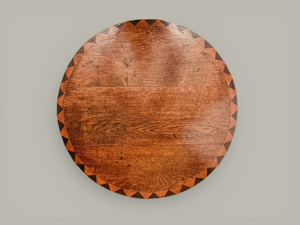 An antique dark oak circular tilt-top pedestal table featuring a geometric inlaid border, a spiral turned column, and carved tripod legs. View VII