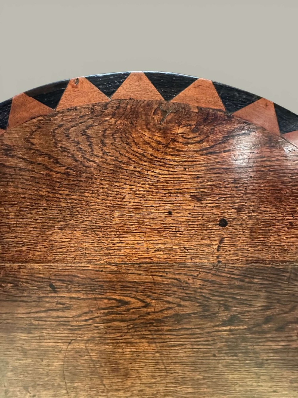 An antique dark oak circular tilt-top pedestal table featuring a geometric inlaid border, a spiral turned column, and carved tripod legs. View IX