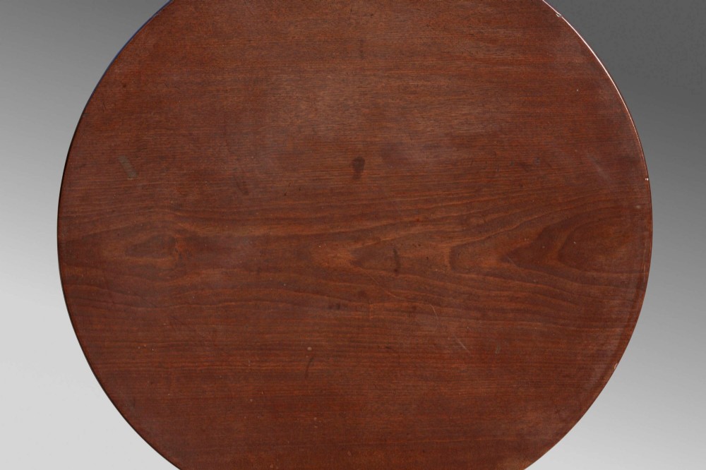 An 18th-century George III mahogany tilt-top table with a circular top raised vertically on a turned stem and splayed tripod cabriole legs. View III