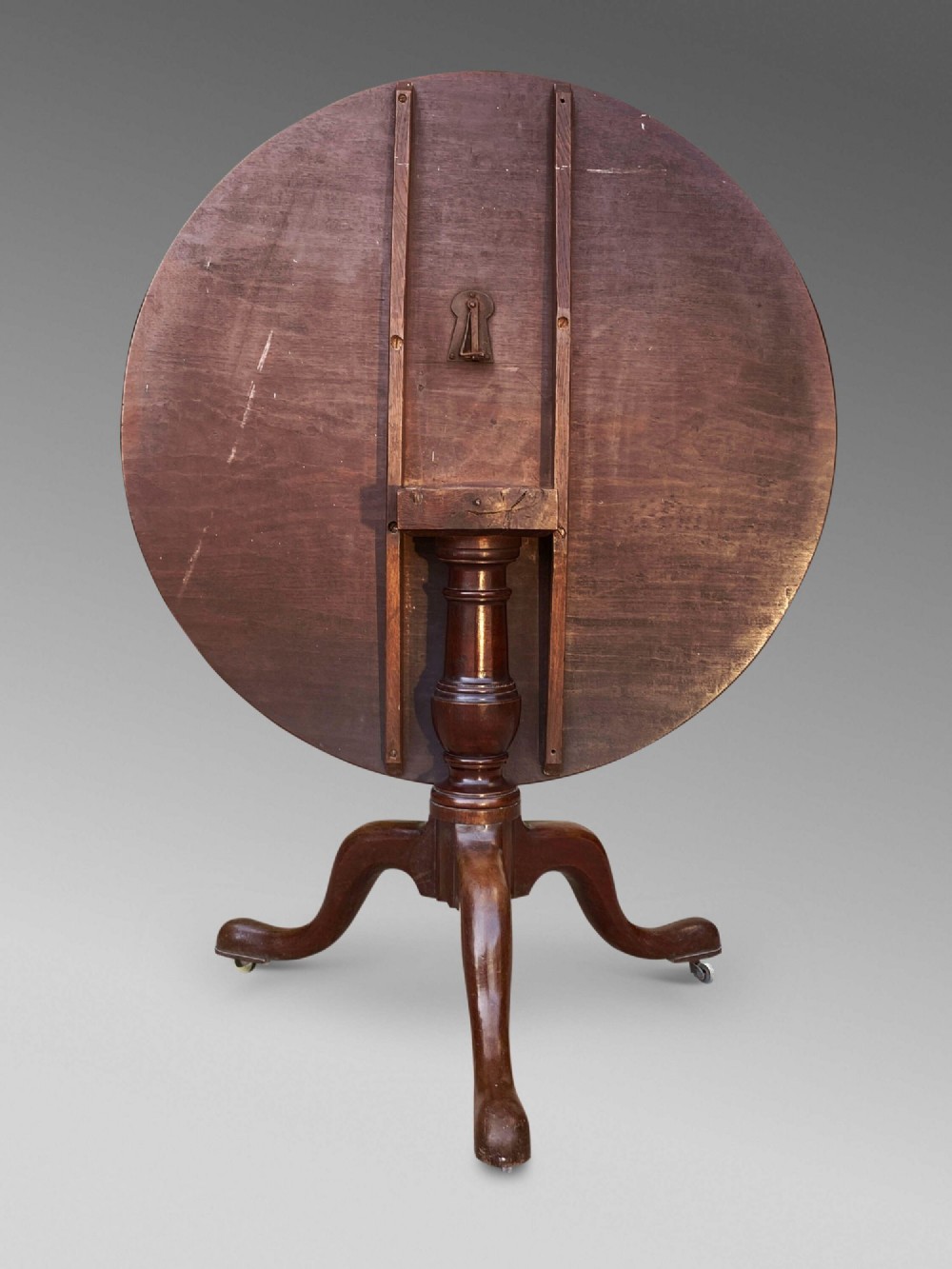 An 18th-century George III mahogany tilt-top table with a circular top raised vertically on a turned stem and splayed tripod cabriole legs. View IV