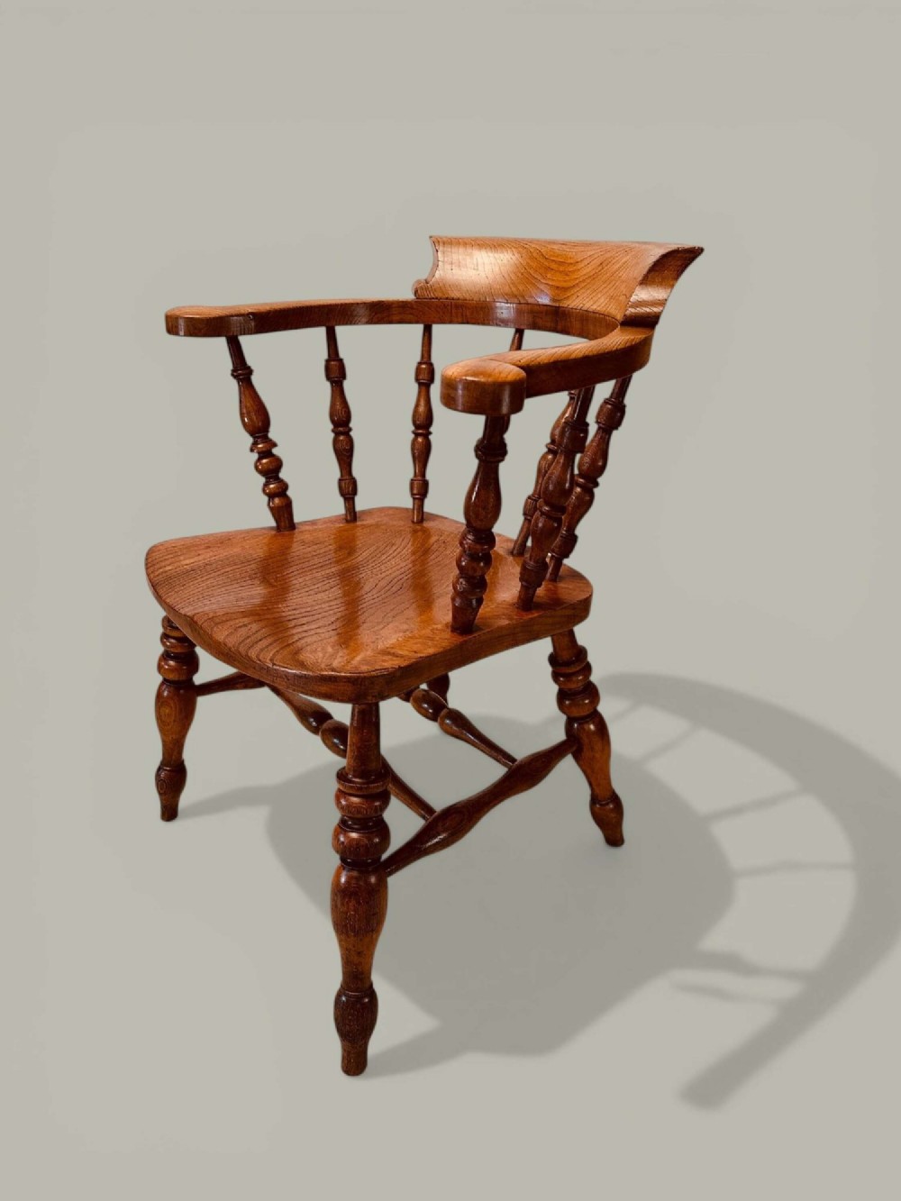 A low-backed wooden Windsor armchair crafted from ash and elm with turned spindles, a curved horseshoe armrest, and a shaped saddle seat. View III