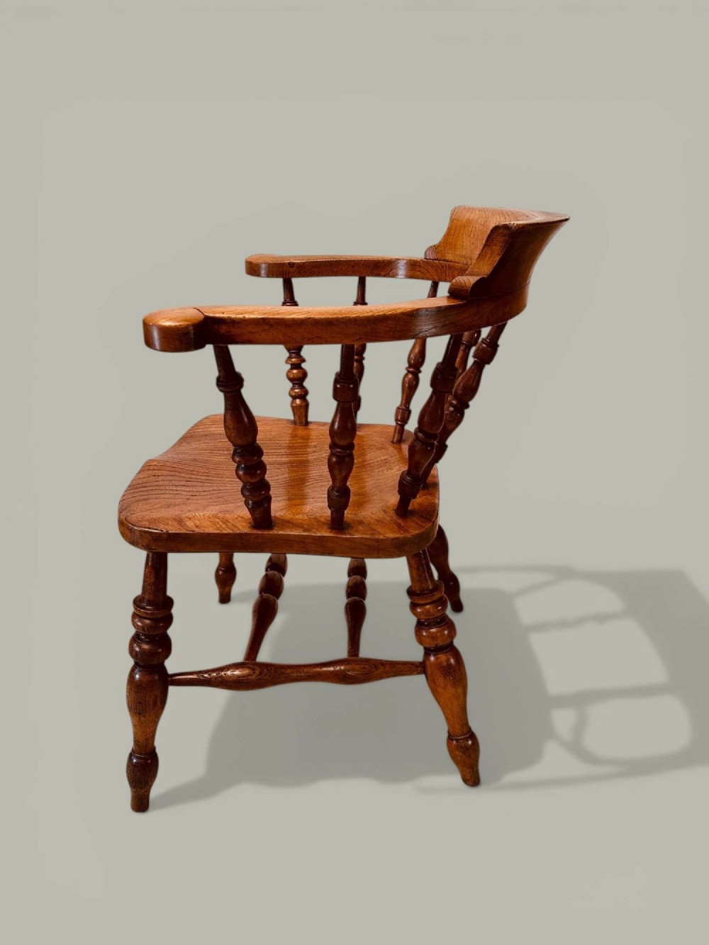 A low-backed wooden Windsor armchair crafted from ash and elm with turned spindles, a curved horseshoe armrest, and a shaped saddle seat. View IV