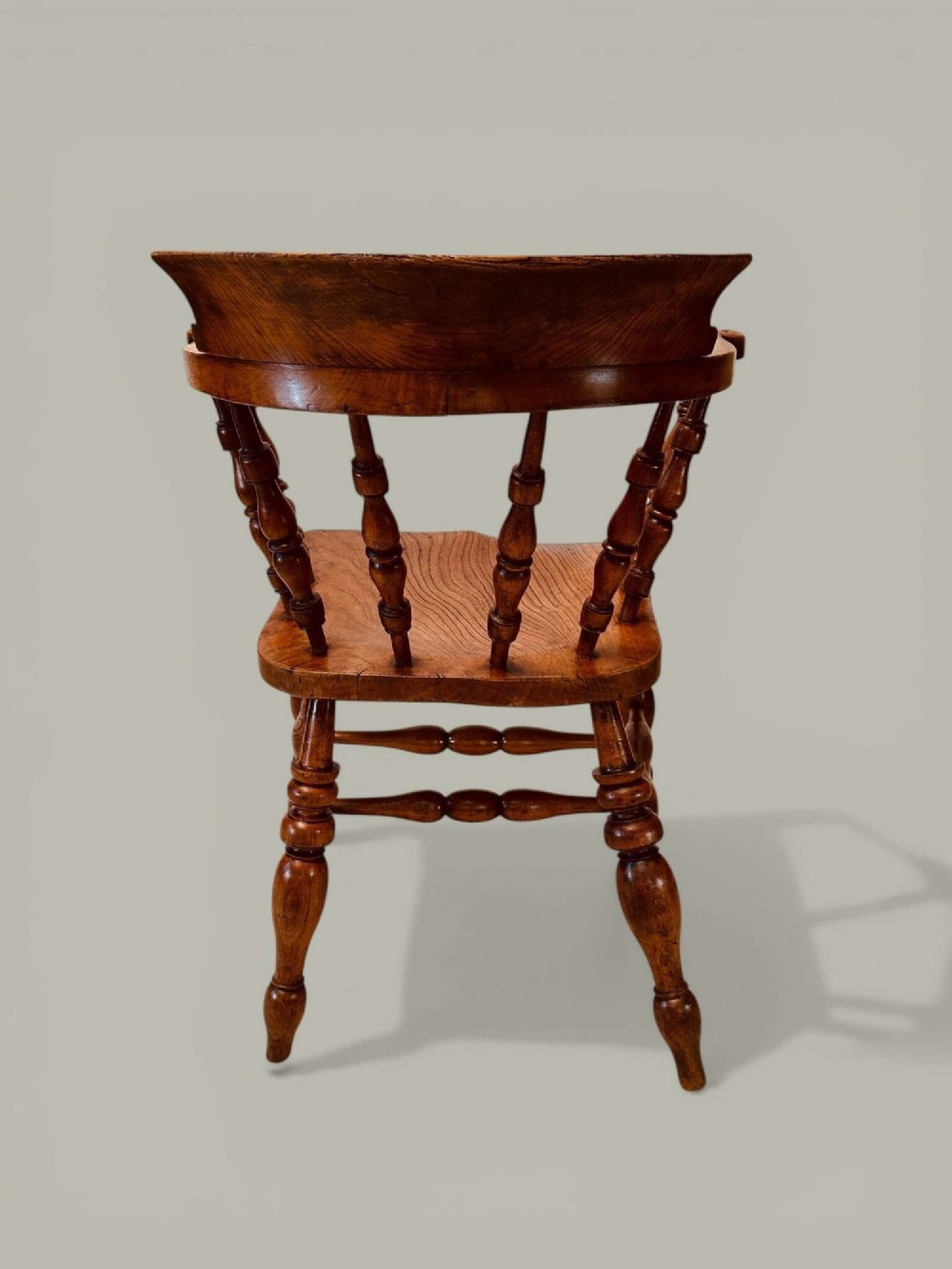 A low-backed wooden Windsor armchair crafted from ash and elm with turned spindles, a curved horseshoe armrest, and a shaped saddle seat. View V