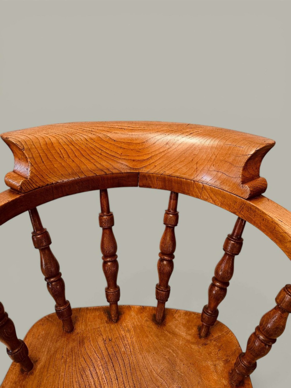 A low-backed wooden Windsor armchair crafted from ash and elm with turned spindles, a curved horseshoe armrest, and a shaped saddle seat. View VII