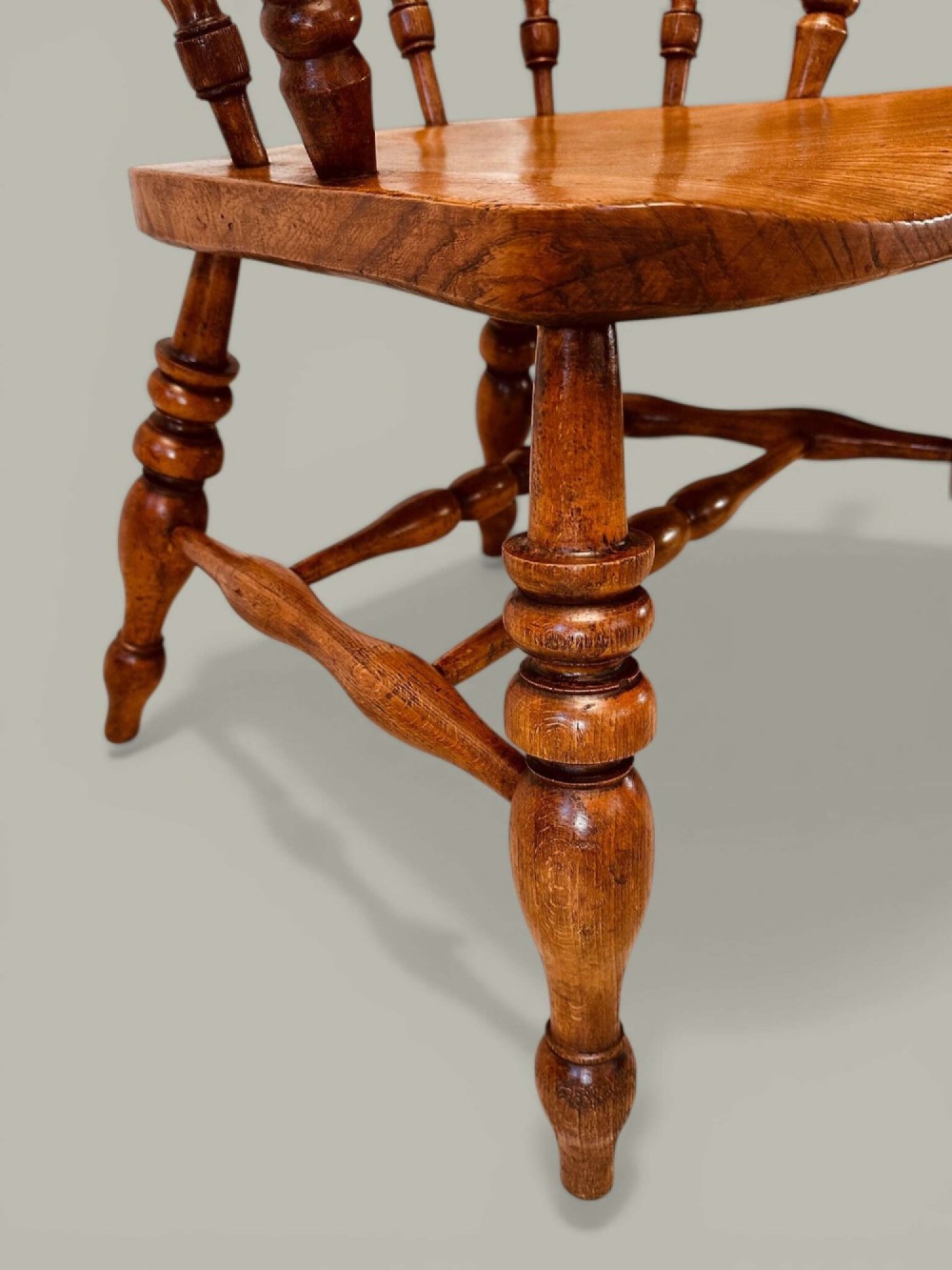 A low-backed wooden Windsor armchair crafted from ash and elm with turned spindles, a curved horseshoe armrest, and a shaped saddle seat. View IX