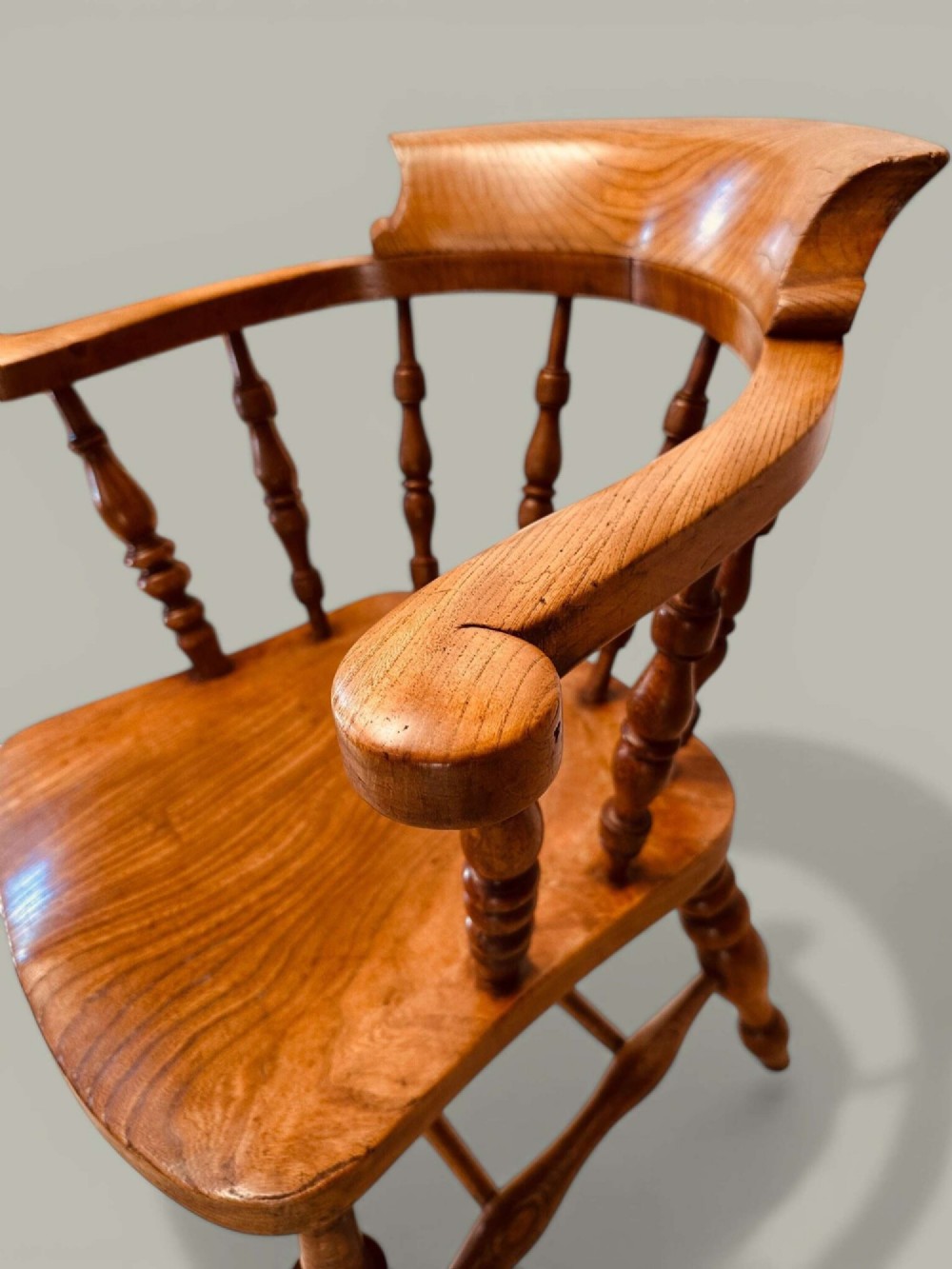 A low-backed wooden Windsor armchair crafted from ash and elm with turned spindles, a curved horseshoe armrest, and a shaped saddle seat. View XI
