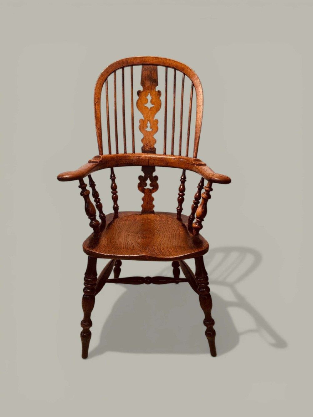A late nineteenth-century Windsor armchair crafted from ash and elm with a hoop back, decorative pierced splat, broad armrests, and turned legs. View II