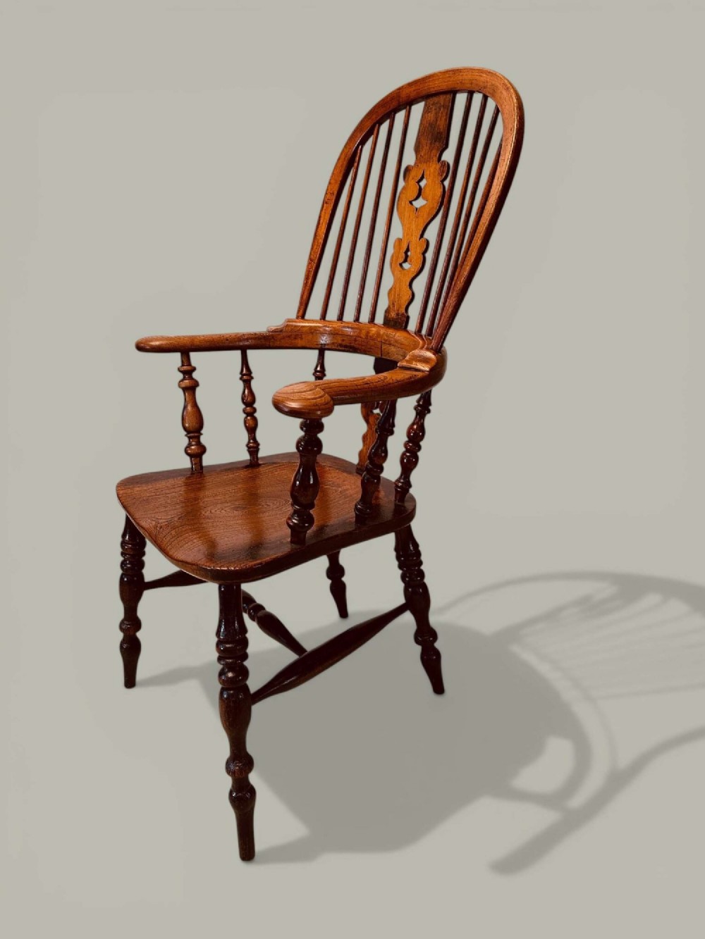 A late nineteenth-century Windsor armchair crafted from ash and elm with a hoop back, decorative pierced splat, broad armrests, and turned legs. View IV