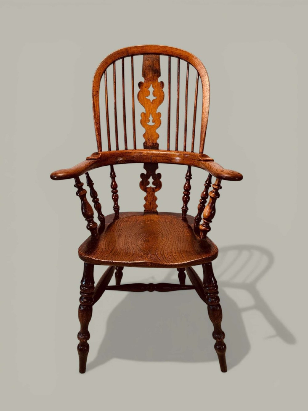 A late nineteenth-century Windsor armchair crafted from ash and elm with a hoop back, decorative pierced splat, broad armrests, and turned legs. View V