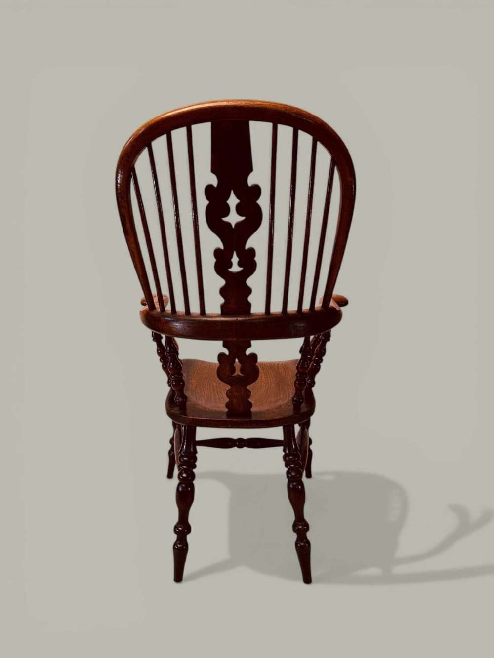 A late nineteenth-century Windsor armchair crafted from ash and elm with a hoop back, decorative pierced splat, broad armrests, and turned legs. View VII