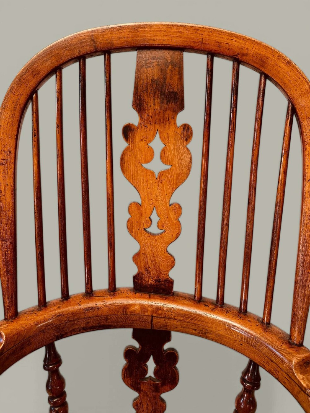 A late nineteenth-century Windsor armchair crafted from ash and elm with a hoop back, decorative pierced splat, broad armrests, and turned legs. View IX