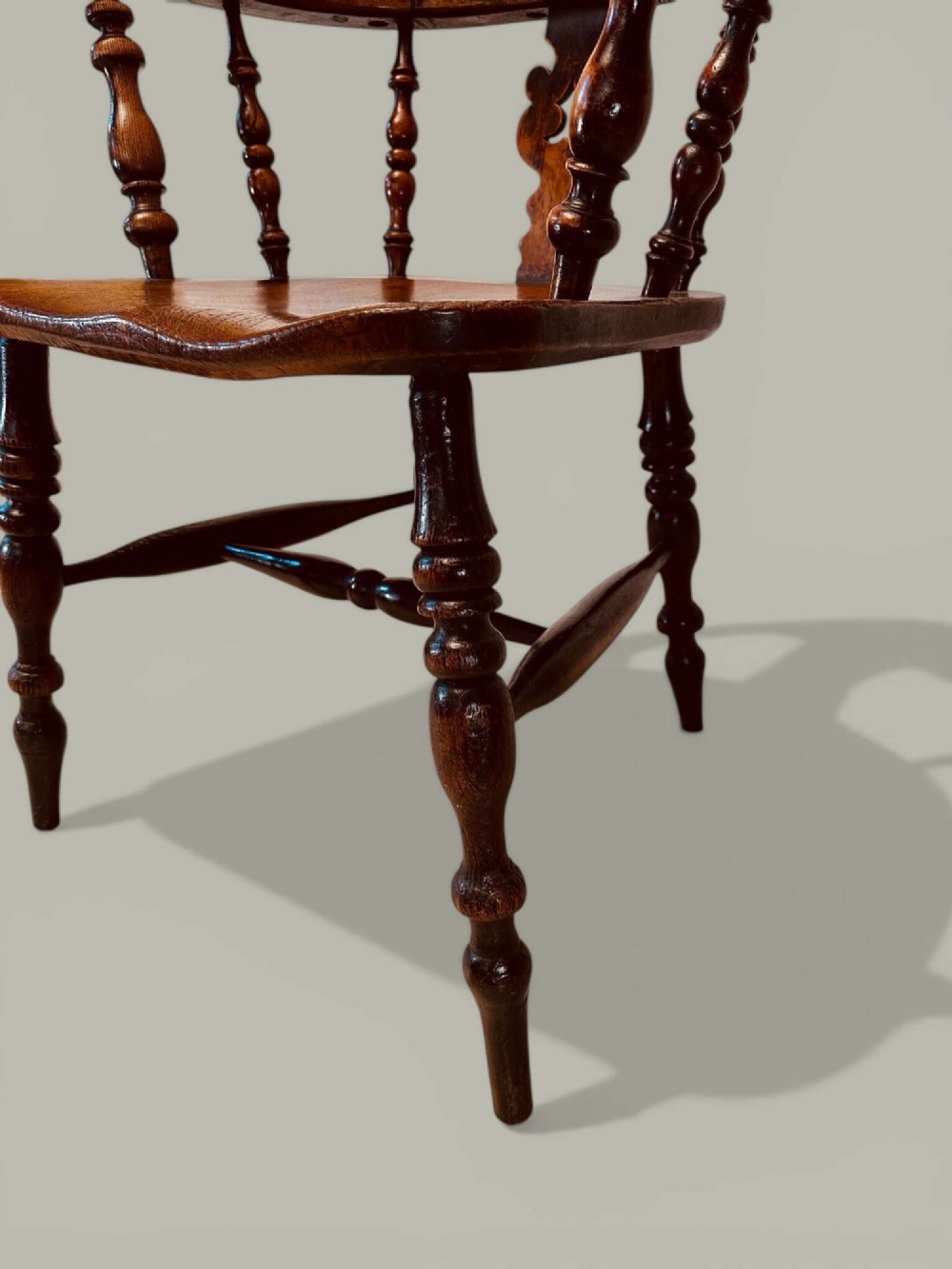 A late nineteenth-century Windsor armchair crafted from ash and elm with a hoop back, decorative pierced splat, broad armrests, and turned legs. View XI