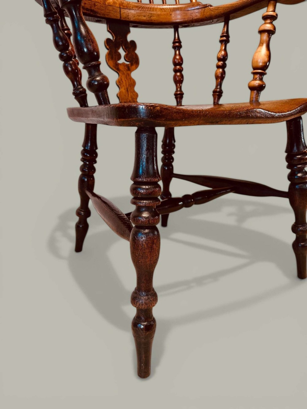 A late nineteenth-century Windsor armchair crafted from ash and elm with a hoop back, decorative pierced splat, broad armrests, and turned legs. View XII