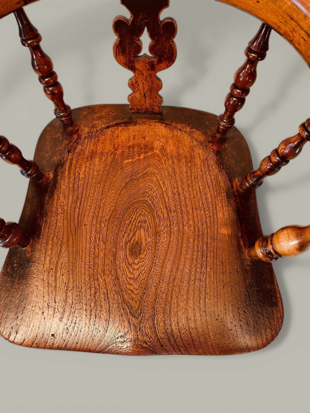 A late nineteenth-century Windsor armchair crafted from ash and elm with a hoop back, decorative pierced splat, broad armrests, and turned legs. View XIII