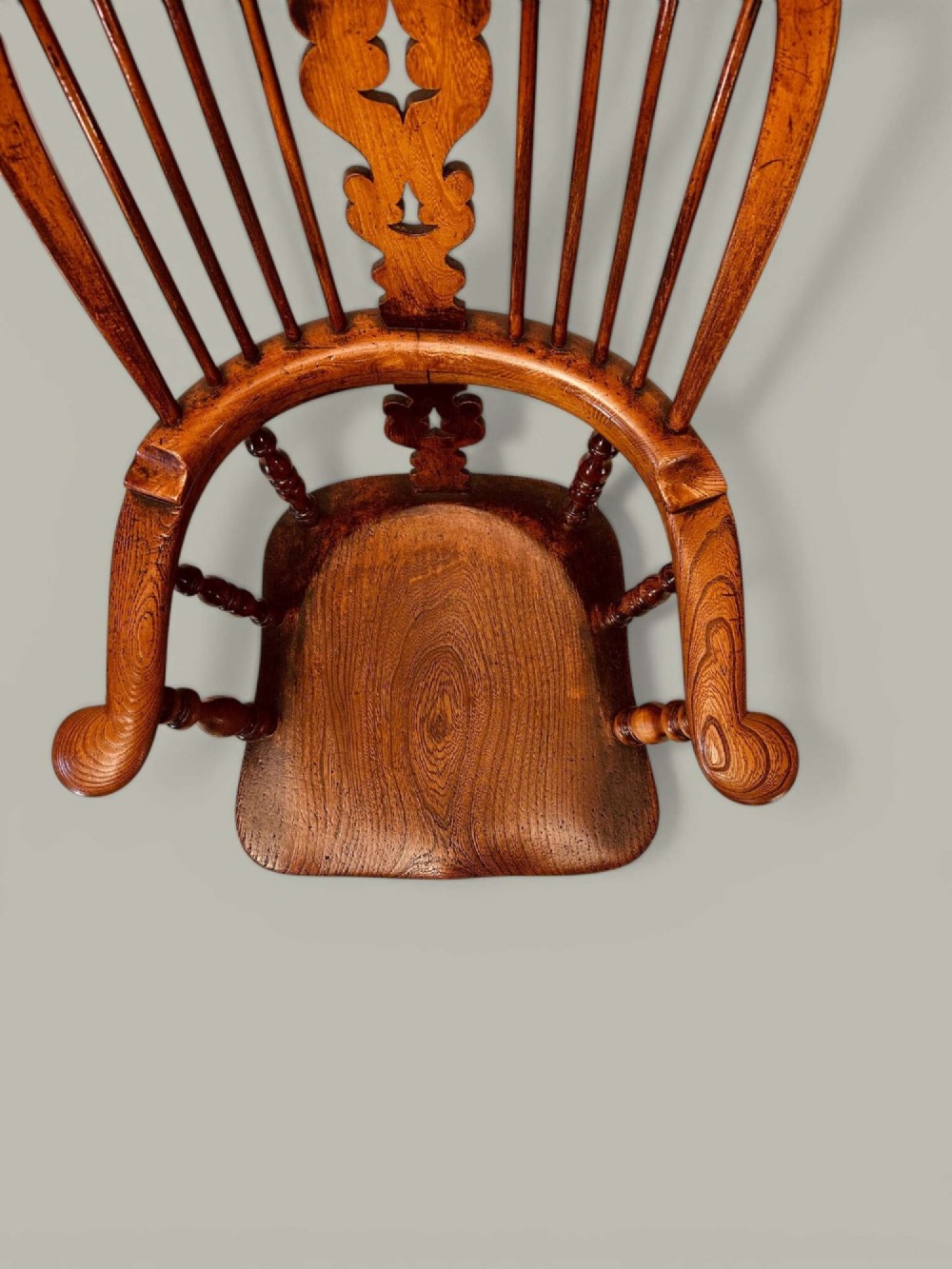 A late nineteenth-century Windsor armchair crafted from ash and elm with a hoop back, decorative pierced splat, broad armrests, and turned legs. View XIV