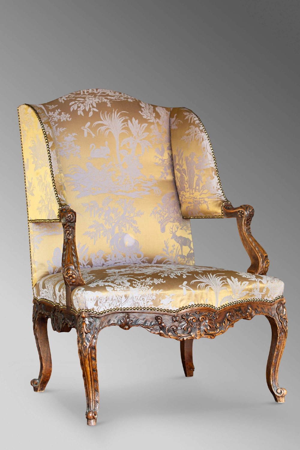 A 19th-century French Louis XV style wingback armchair with carved wood framing, cabriole legs, and gold pattern damask upholstery. View II