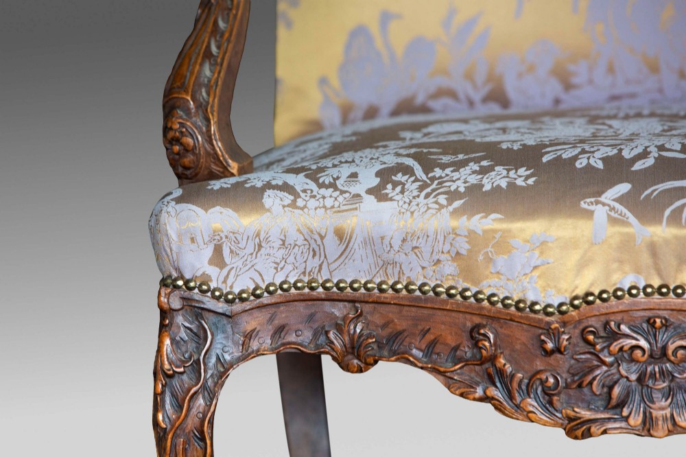 A 19th-century French Louis XV style wingback armchair with carved wood framing, cabriole legs, and gold pattern damask upholstery. View IV