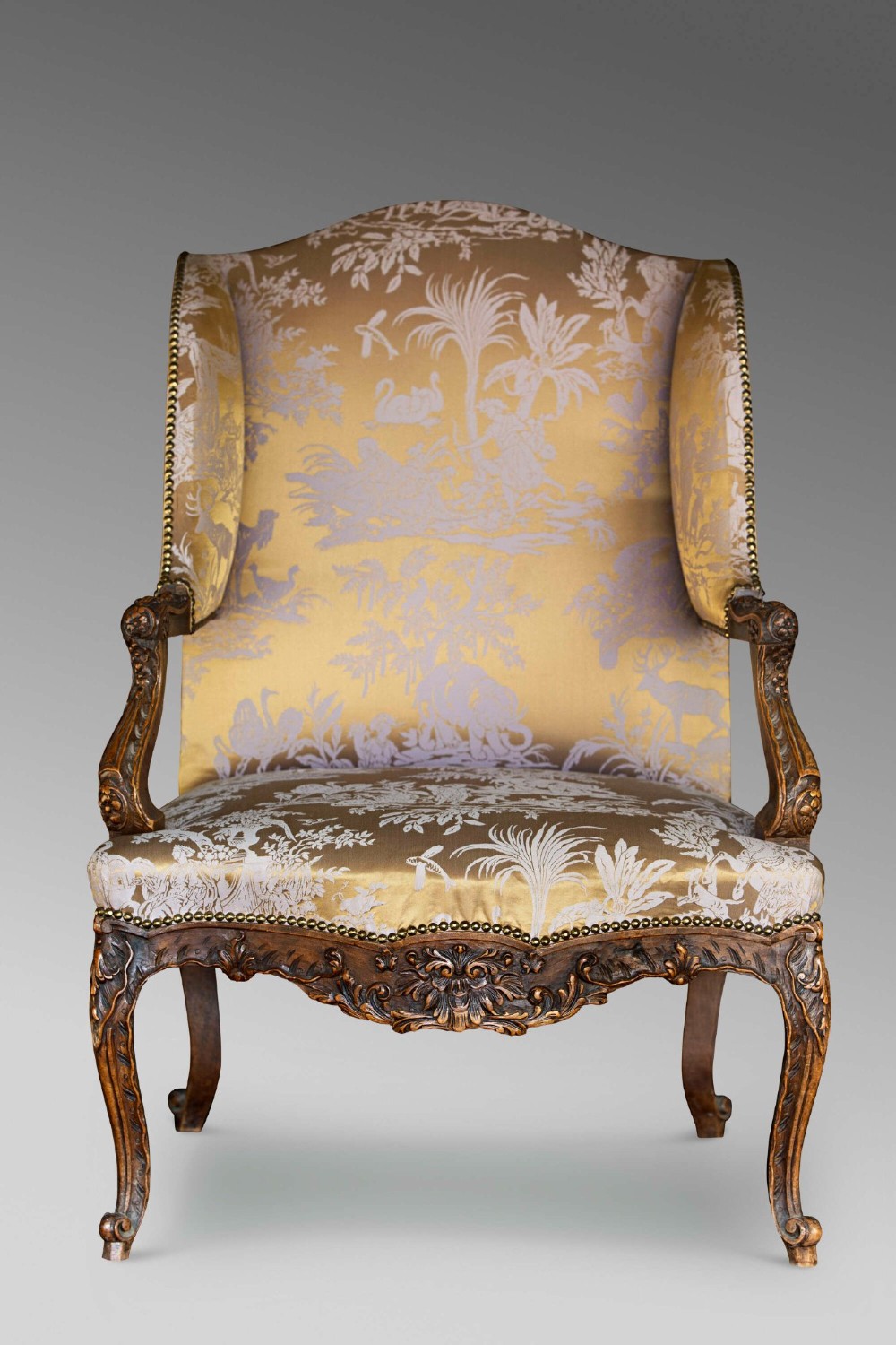 A 19th-century French Louis XV style wingback armchair with carved wood framing, cabriole legs, and gold pattern damask upholstery. View VII