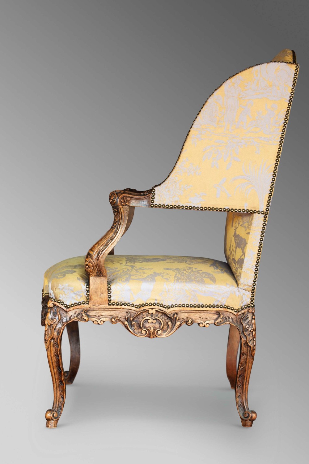 A 19th-century French Louis XV style wingback armchair with carved wood framing, cabriole legs, and gold pattern damask upholstery. View XIV