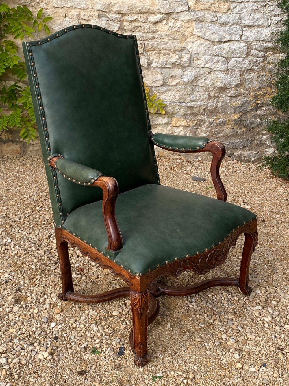 An eighteenth-century French walnut fauteuil armchair upholstered in dark green leather with brass studding, carved apron details, and curved legs. View III