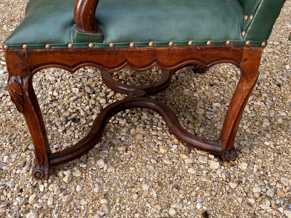 An eighteenth-century French walnut fauteuil armchair upholstered in dark green leather with brass studding, carved apron details, and curved legs. View VII