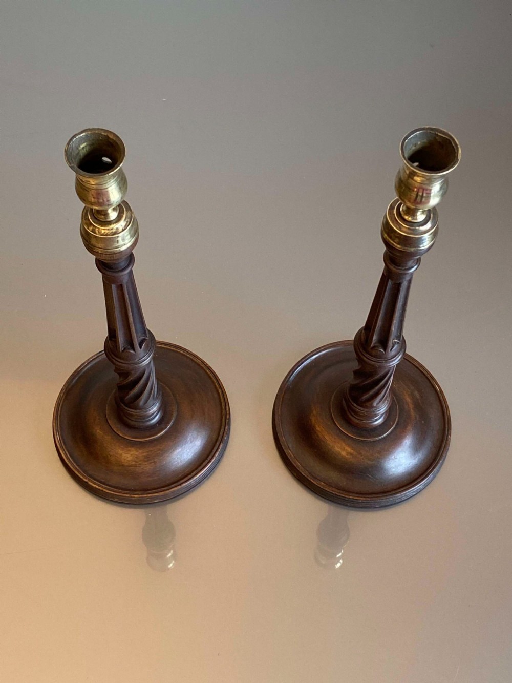 A pair of turned dark mahogany candlesticks featuring fluted and spiral columns topped with brass nozzles on circular bases. View II