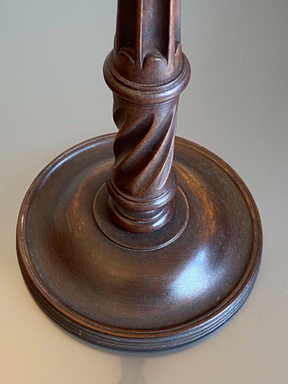 A pair of turned dark mahogany candlesticks featuring fluted and spiral columns topped with brass nozzles on circular bases. View V