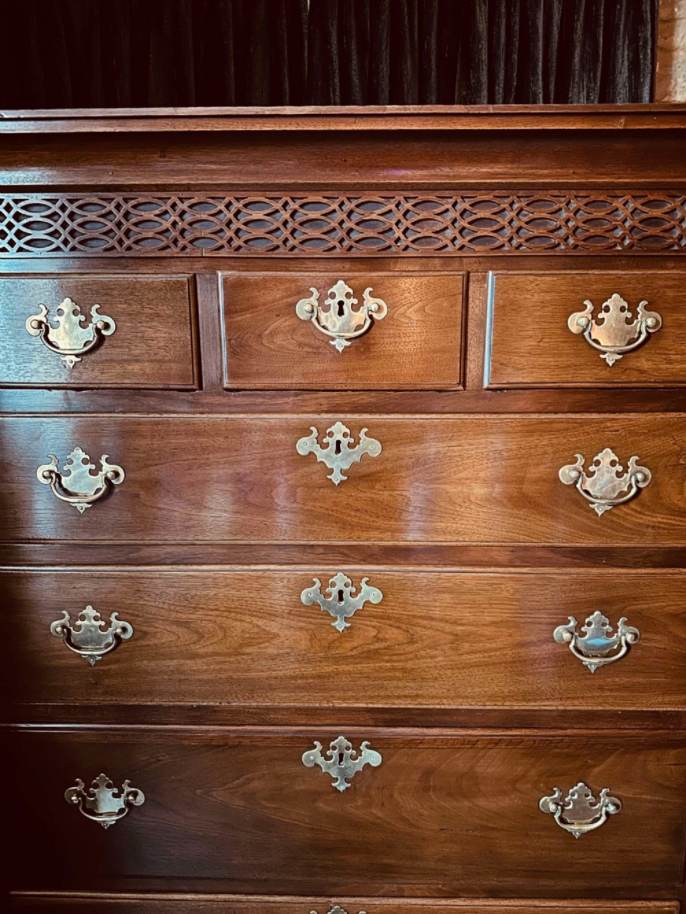 A tall 19th-century walnut chest of drawers featuring a carved fretwork frieze, brass backplate handles, and graduated drawer fronts. View IV