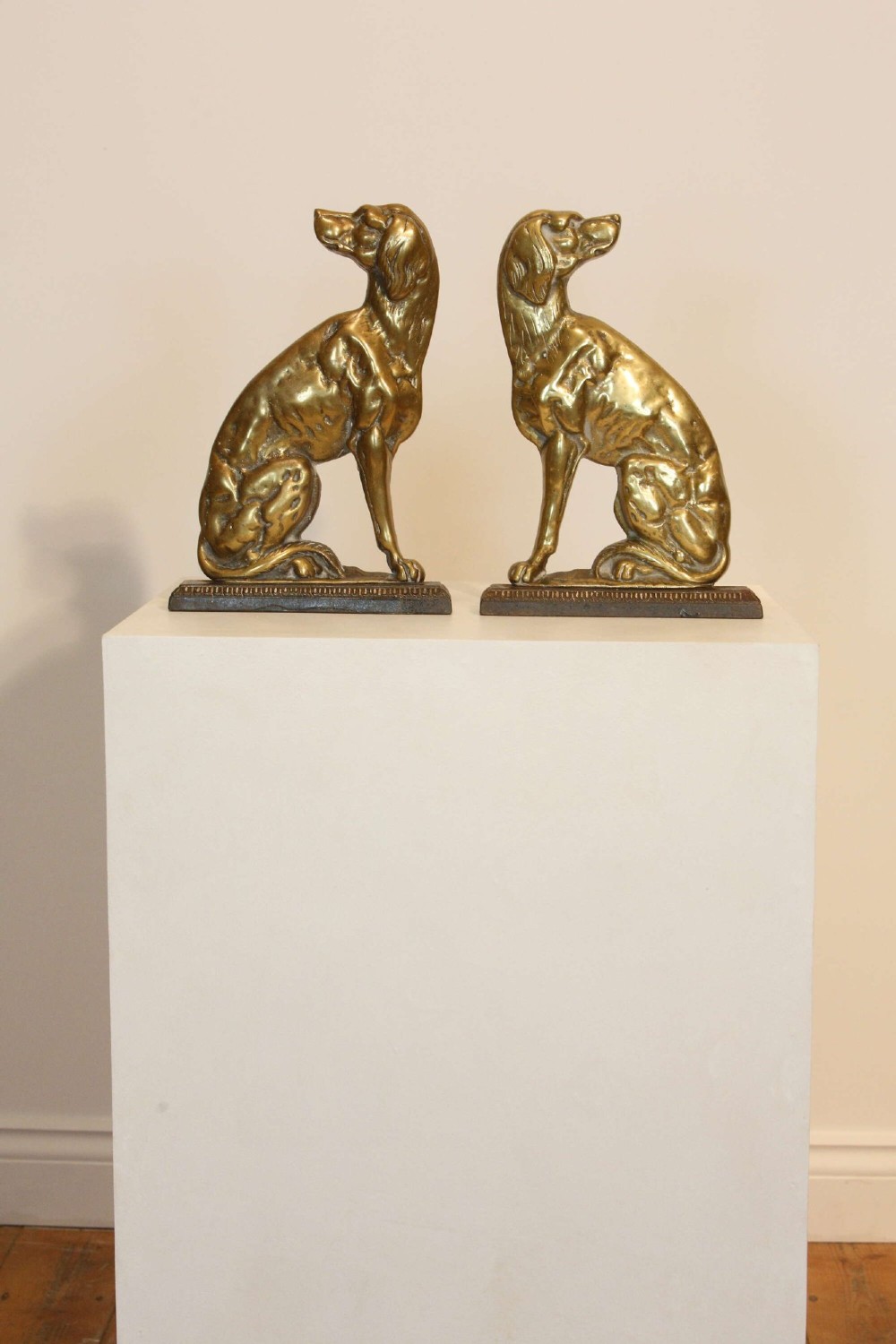 A pair of 19th-century cast brass doorstops crafted in the likeness of seated hunting dogs on rectangular bases. View II