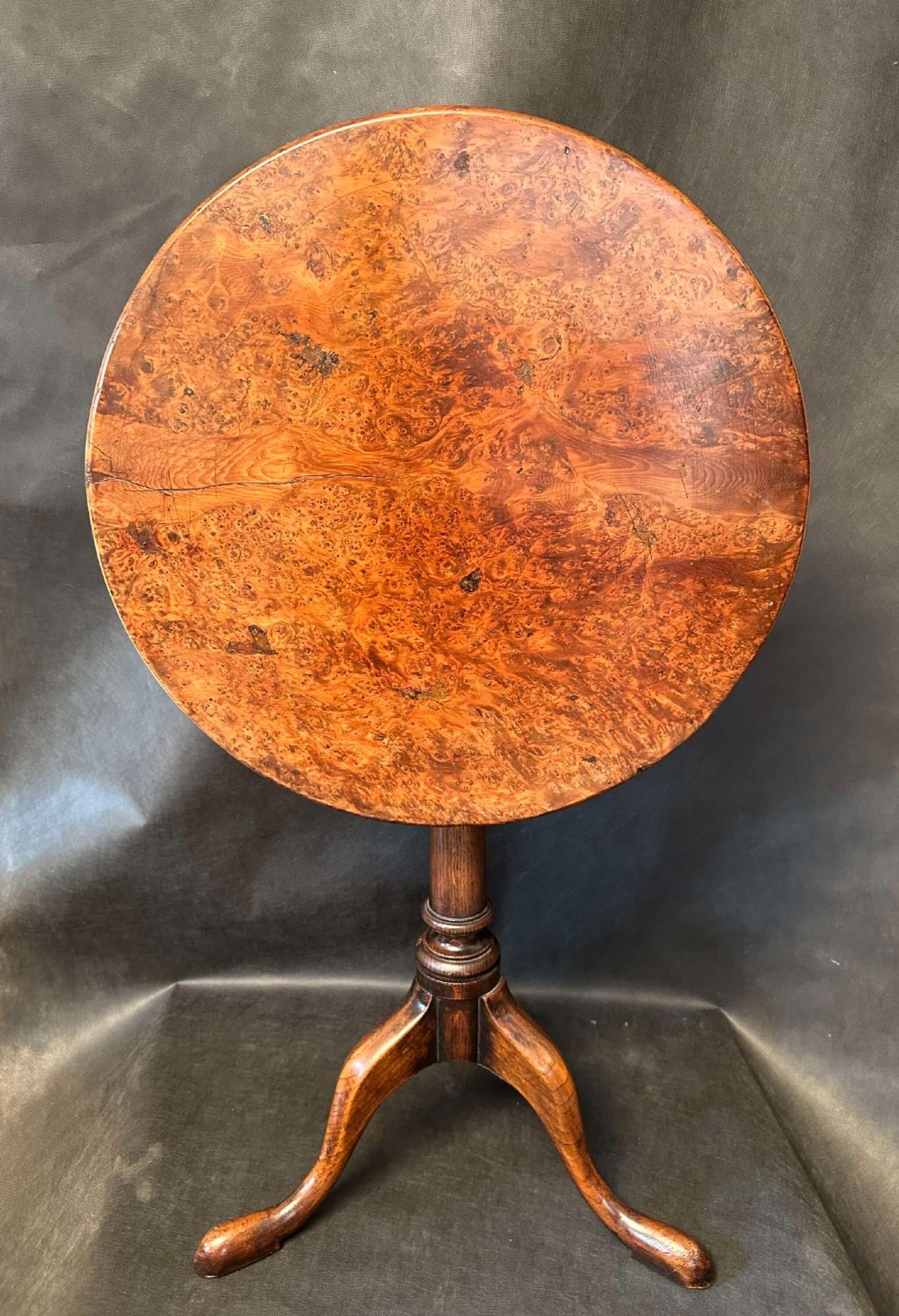 A Georgian circular occasional table crafted from burr yew wood featuring a turned central pedestal and a tripod base.