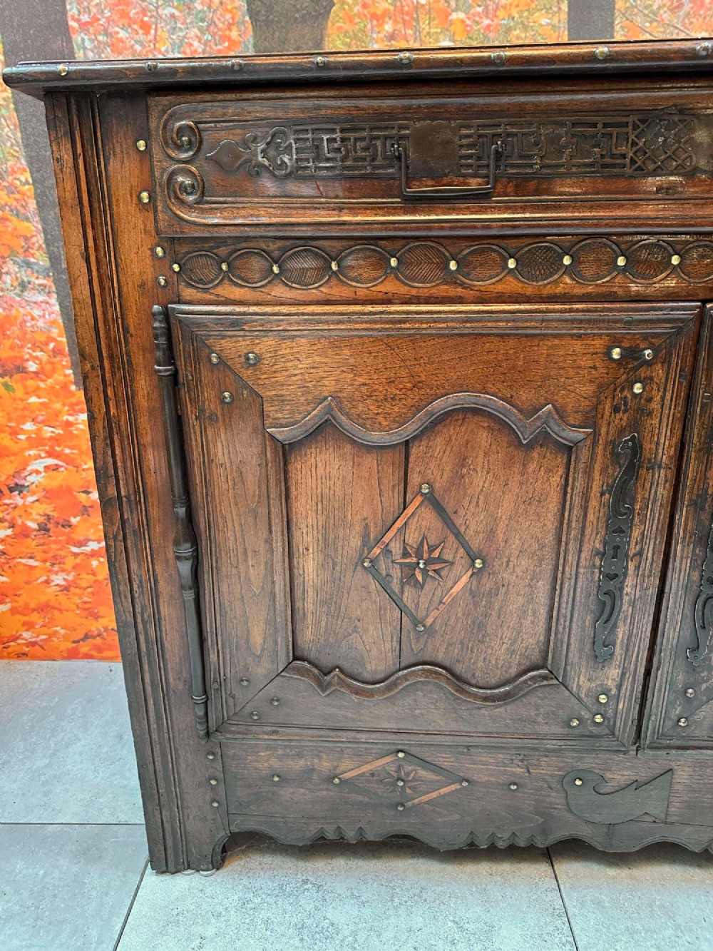 An antique French chestnut buffet featuring a carved top drawer band, two moulded door panels with carved star motifs, and iron hardware. View II