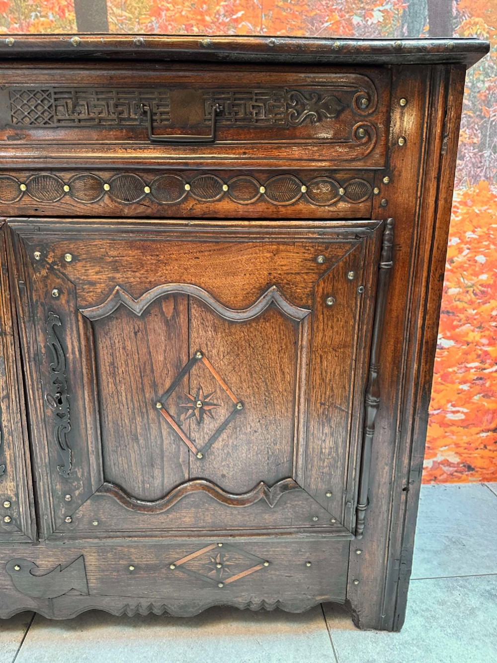 An antique French chestnut buffet featuring a carved top drawer band, two moulded door panels with carved star motifs, and iron hardware. View III
