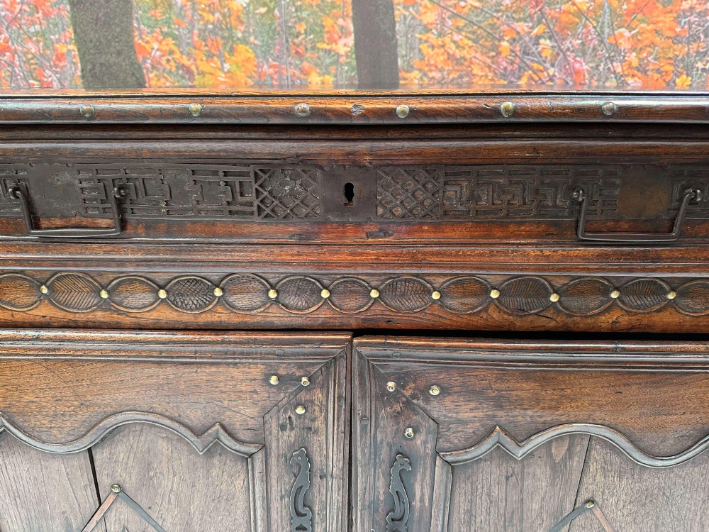 An antique French chestnut buffet featuring a carved top drawer band, two moulded door panels with carved star motifs, and iron hardware. View IV