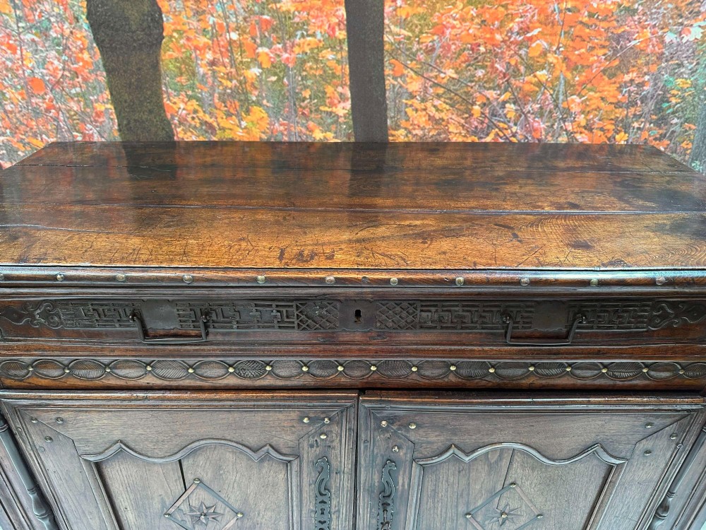 An antique French chestnut buffet featuring a carved top drawer band, two moulded door panels with carved star motifs, and iron hardware. View V