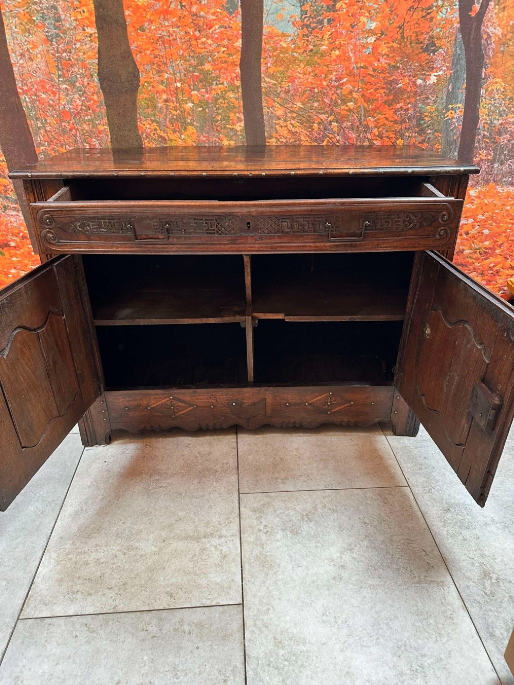 An antique French chestnut buffet featuring a carved top drawer band, two moulded door panels with carved star motifs, and iron hardware. View VI