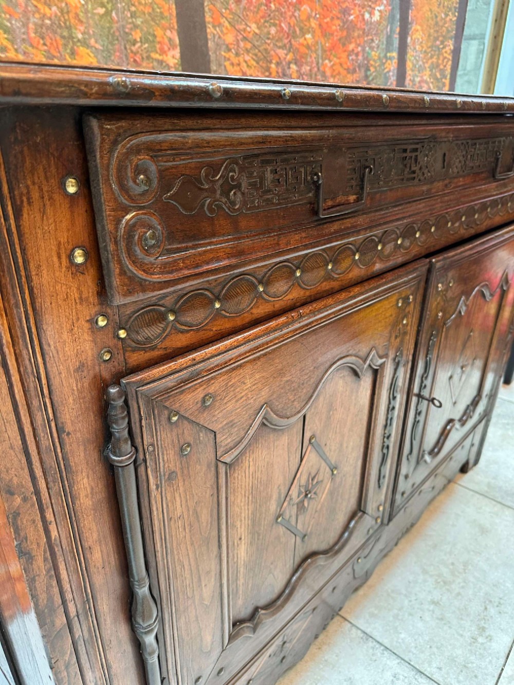 An antique French chestnut buffet featuring a carved top drawer band, two moulded door panels with carved star motifs, and iron hardware. View VII