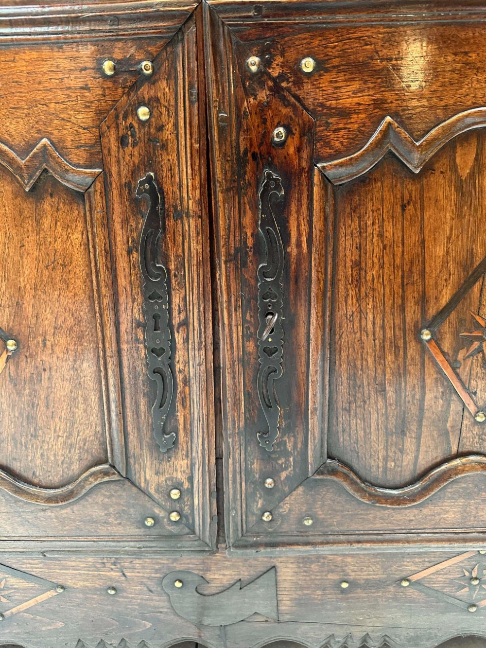 An antique French chestnut buffet featuring a carved top drawer band, two moulded door panels with carved star motifs, and iron hardware. View X