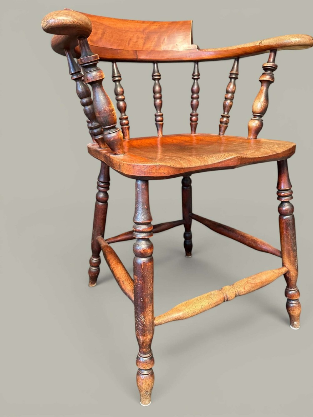 An antique alder wood Windsor captains chair featuring turned spindles, a contoured saddle seat, and high turned legs joined by stretchers. View II