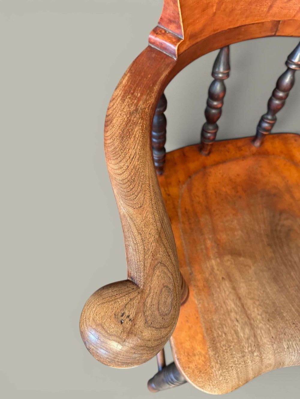 An antique alder wood Windsor captains chair featuring turned spindles, a contoured saddle seat, and high turned legs joined by stretchers. View VII
