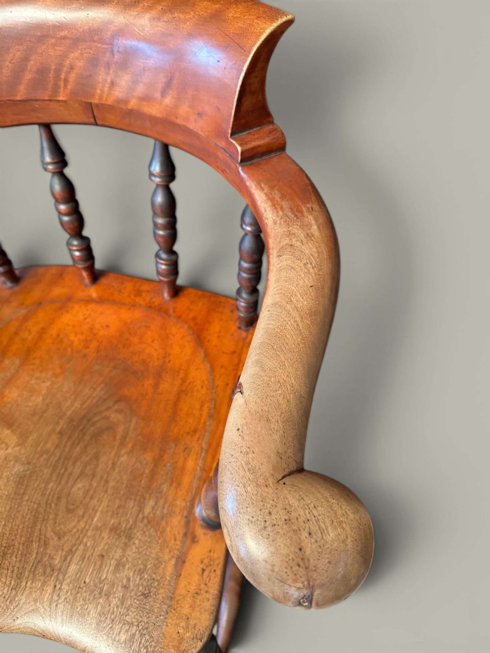 An antique alder wood Windsor captains chair featuring turned spindles, a contoured saddle seat, and high turned legs joined by stretchers. View VIII
