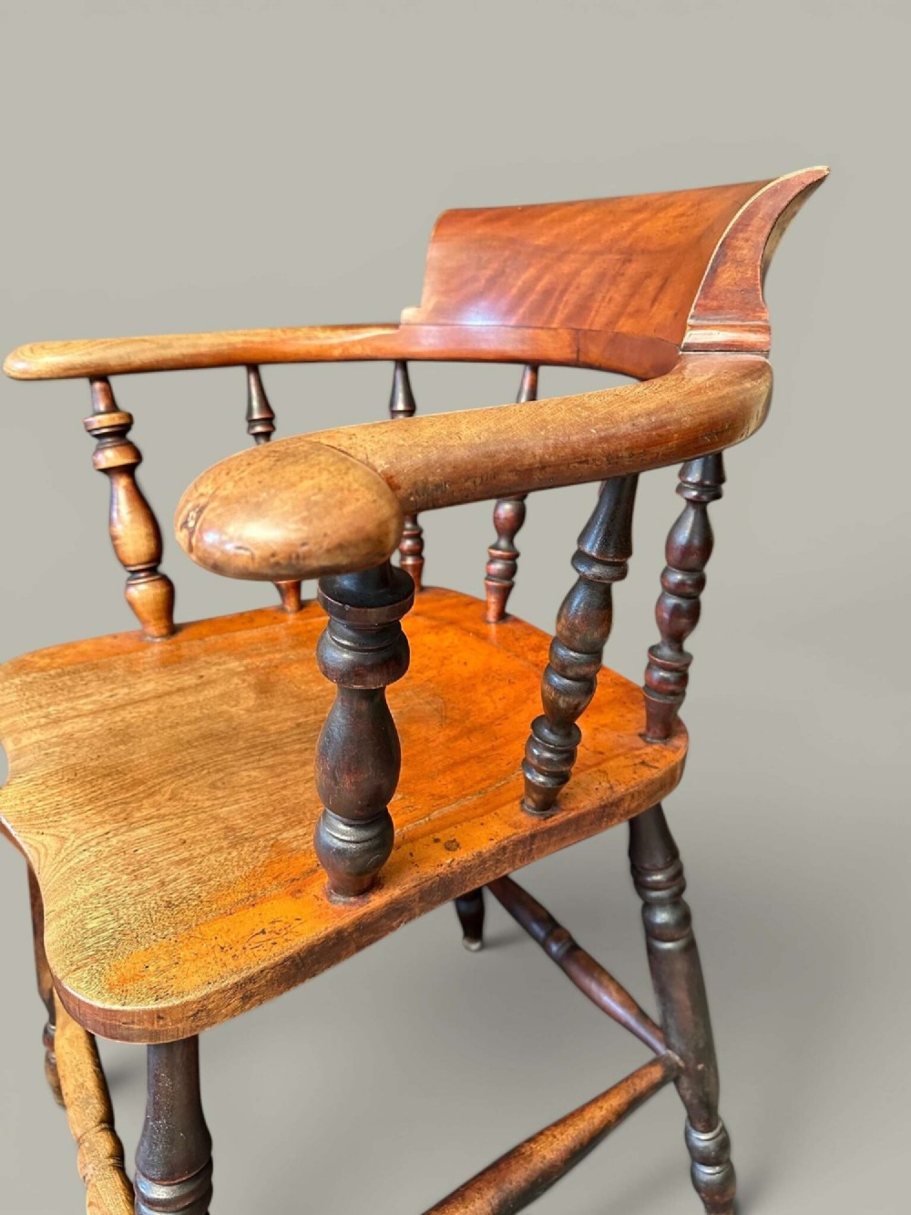 An antique alder wood Windsor captains chair featuring turned spindles, a contoured saddle seat, and high turned legs joined by stretchers. View X